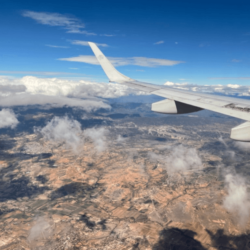 View from a plane window over clouds and dry countryside
